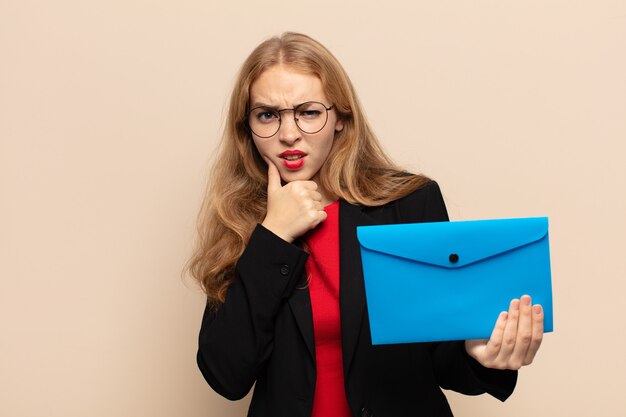 Blonde woman with mouth and eyes wide open and hand on chin, feeling unpleasantly shocked, saying what or wow