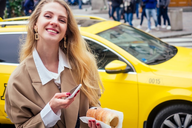 Foto una donna bionda con il telefono in una strada in una città europea che mangia trdlo a praha.