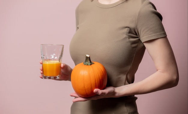 Blonde woman with pumpkin juice on pink