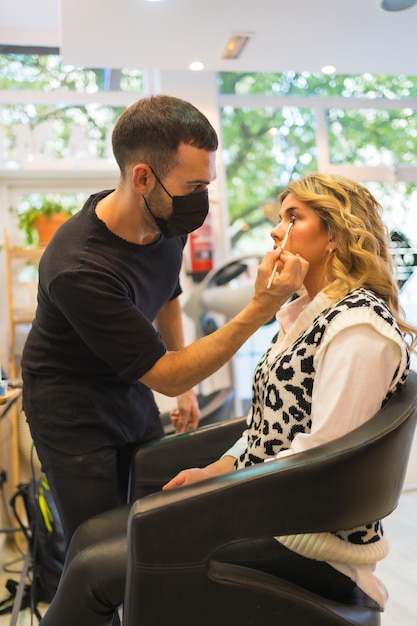 Blonde woman with receiving a makeup before the photoshoot