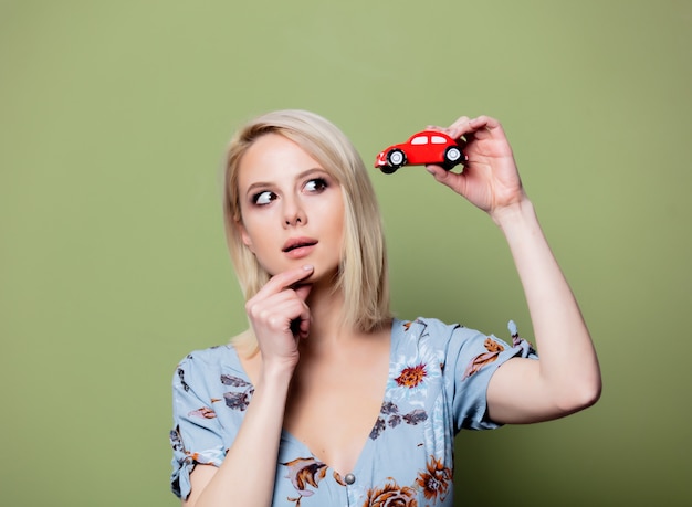 Blonde woman with red car on green wall