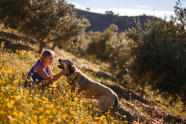 Donna bionda con mastino spagnolo su un campo di fiori gialli