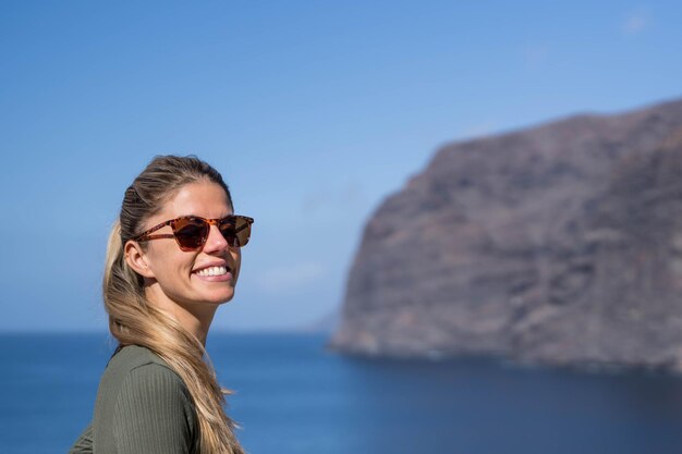 Blonde woman with sunglasses in the nature at the sea