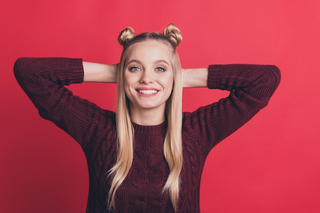 blonde woman with top-knots posing against the red wall