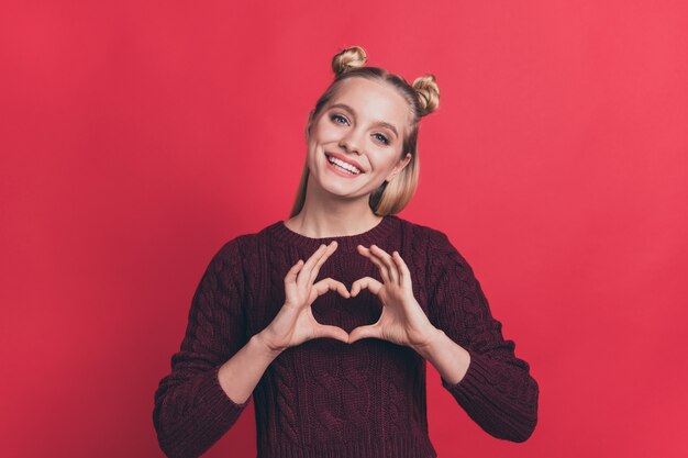 blonde woman with top-knots posing against the red wall