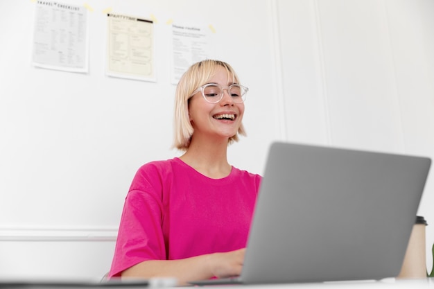 Foto donna bionda che lavora da casa sul suo laptop