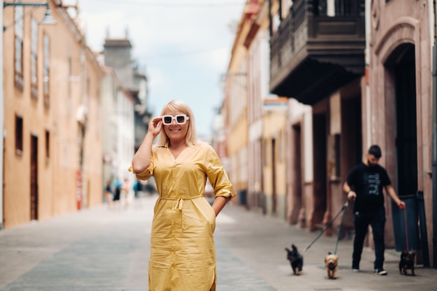 Una donna bionda in un abito estivo giallo si trova sulla strada della città vecchia di la laguna sull'isola di tenerife.spagna, isole canarie.