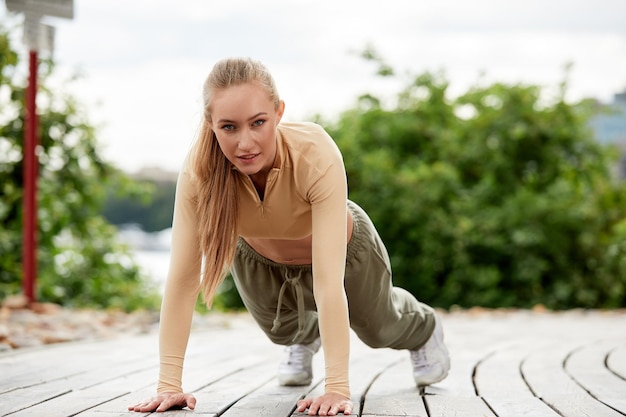 Blonde young athletic woman doing working out in a park in an urban environment Attractive athletic woman exercising outdoors in the morning copy space Health fitness concept