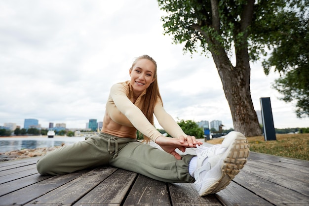 Bionda giovane donna atletica facendo allenamento in un parco in un ambiente urbano attraente donna atletica che si esercita all'aperto nello spazio della copia del mattino concetto di fitness salute