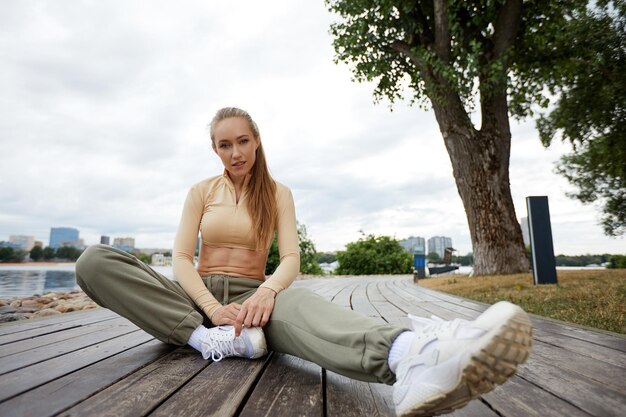 Blonde young athletic woman working out in a park in an urban environment Attractive athletic woman exercising outdoors in the morning copy space Health fitness concept