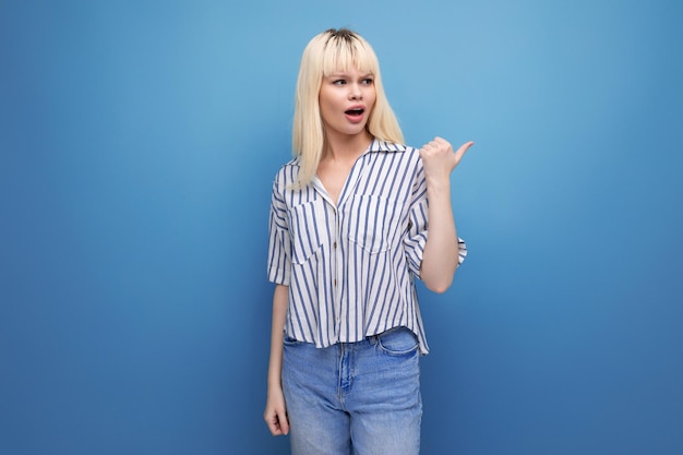 Blonde young female adult in blouse pointing finger to the side isolated background