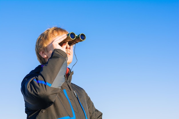 Фото Блондинка смотрит в бинокль на природе парень смотрит в бинокль на голубое небо концепция путешествий и дикой природы