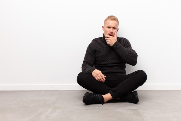 blonde young man sitting and feeling amazed