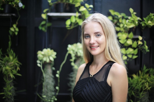 Blonde young woman against green background smiling and posing on background of vineyards