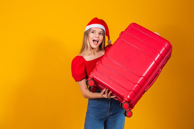 Blonde young woman in christmas outfit and travel bag. Christmas travel concept