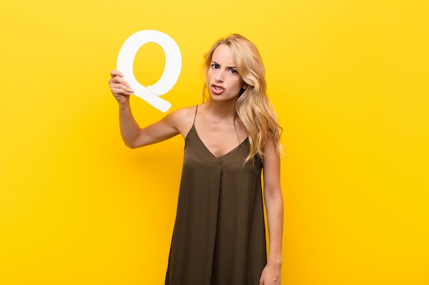 blonde young woman in a dress holding the letter q