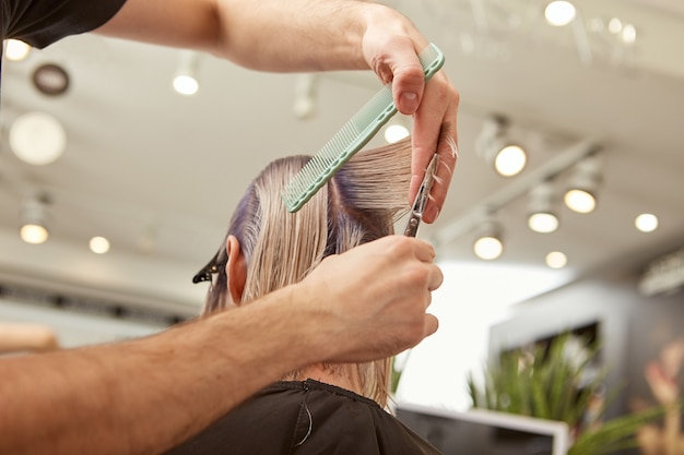 Photo blonde young woman getting haircut in beauty salon