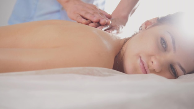 Blonde young woman model receiving relaxing massage in spa room, close up view