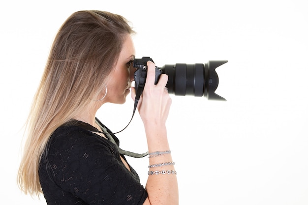 Blonde young woman profile with professional digital SLR camera on white