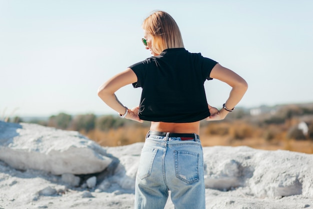 Blonde young woman taking off black t-shirt