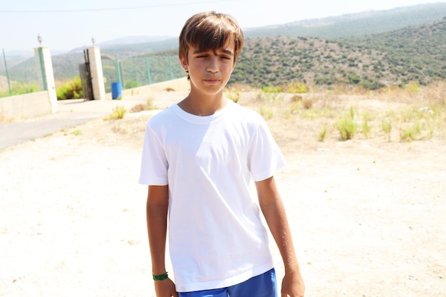 Blonde Youth Boy in White Shirt and Blue Shorts Enjoying Summer Sun in Nature