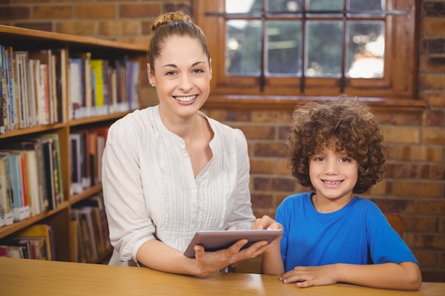 Blondeleraar en leerling die tablet in de bibliotheek gebruiken