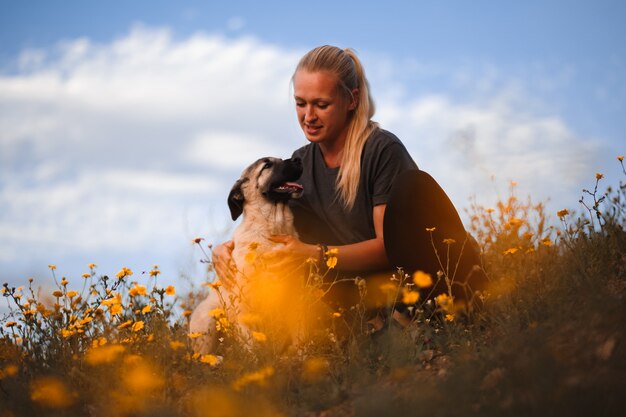 Blondemeisje het spelen met puppy Spaanse mastiff op een gebied van gele bloemen