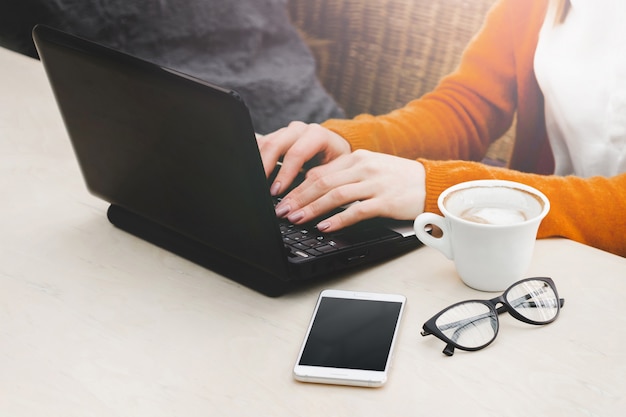 Blondemeisje in een koffie met laptop en een koffie. Jong meisje die freelancer aan laptop werken