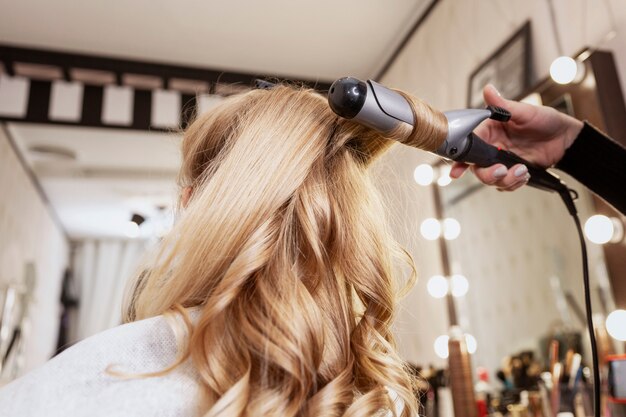 Blondemeisje in een schoonheidssalon die een kapsel doen. Detailopname.