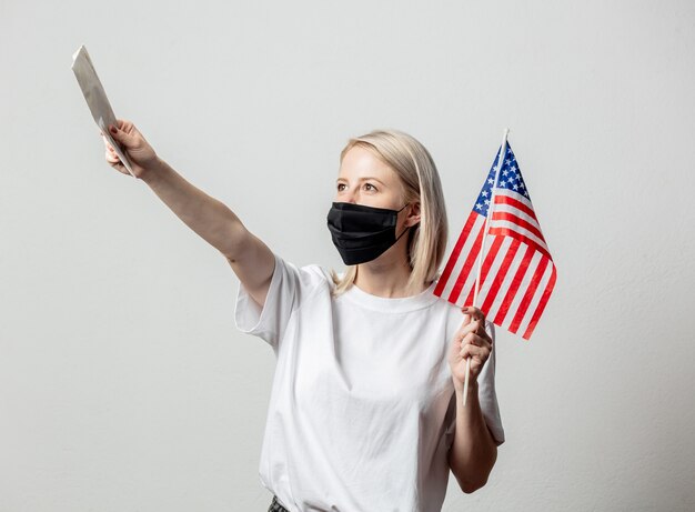 Blondemeisje in gezichtsmasker met de vlag en het geld van de VS.