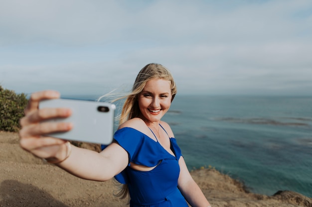 Blondevrouw die foto&#39;s met haar telefoon nemen