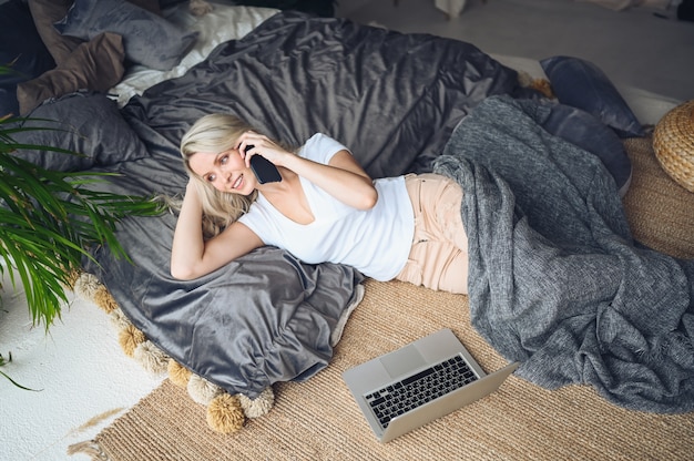 Blondevrouw die op de telefoon in de slaapkamer spreken