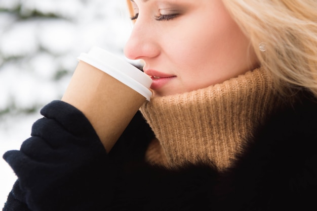 Blondevrouw het drinken koffie in de winterpark