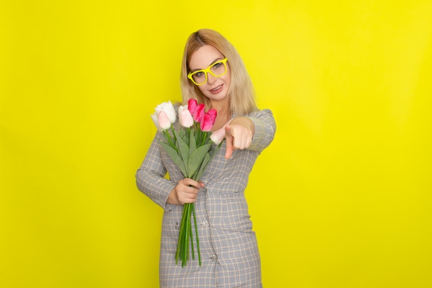 Foto blondevrouw in het boeket van de holdings tulpen van de plaidkleding