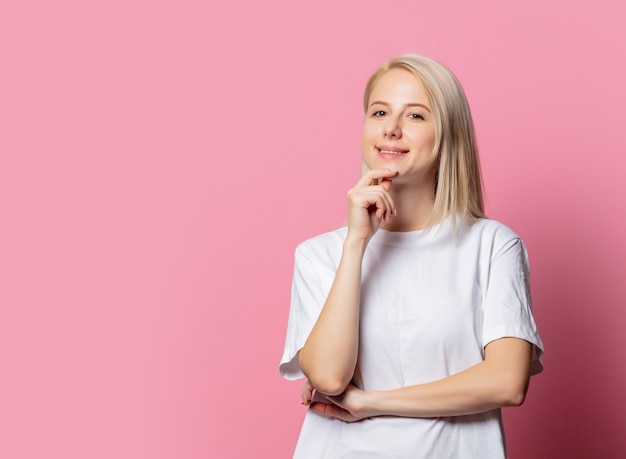 Blondevrouw in witte t-shirt op roze