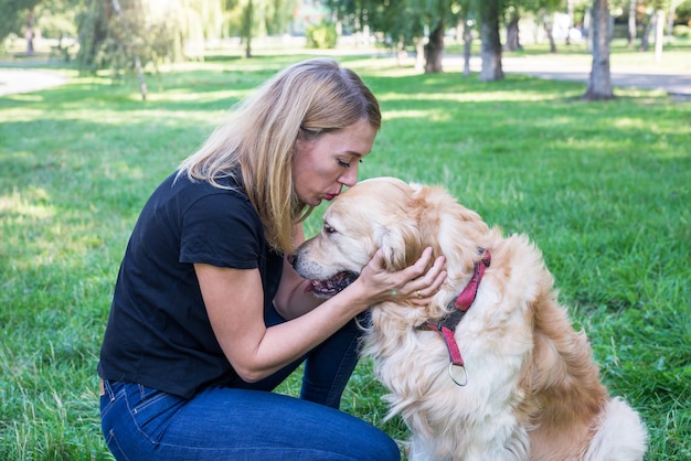 Blondevrouw met haar retrieverhond in de zomerpark