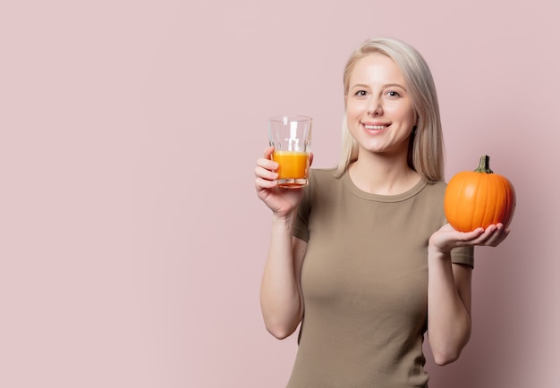 Blondevrouw met pompoensap op roze