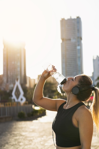 Blondharige vrouw drinkt water na sporten