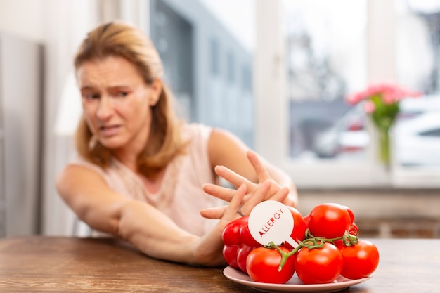 Blondharige vrouw met overgevoeligheid voor allergenen die geen tomaten eet