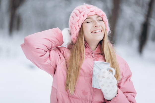 Foto blondiemeisje met kop hete thee buiten in winterpark