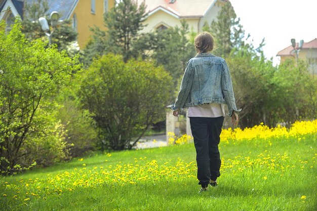 blondine in vrijetijdskleding loopt op een groen gazon met gele bloemen