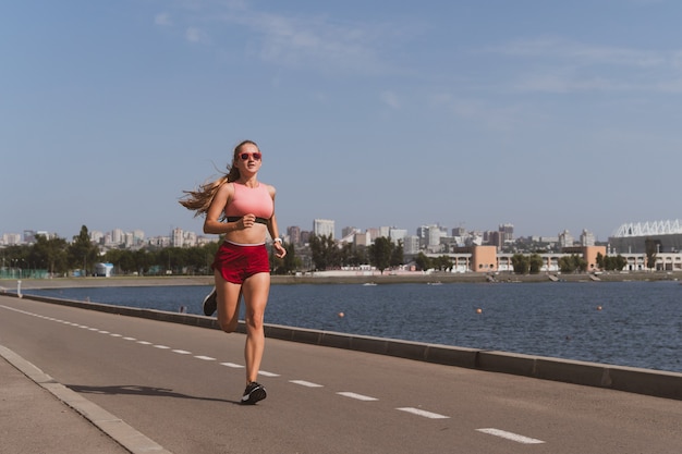 Blondy sportieve vrouw met lang haar loopt in het stadion