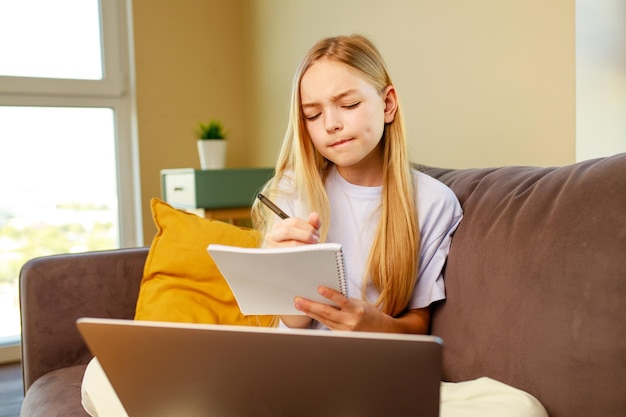 Blonge haar klein meisje met behulp van een laptop thuis huiswerk maken Terug naar school concept