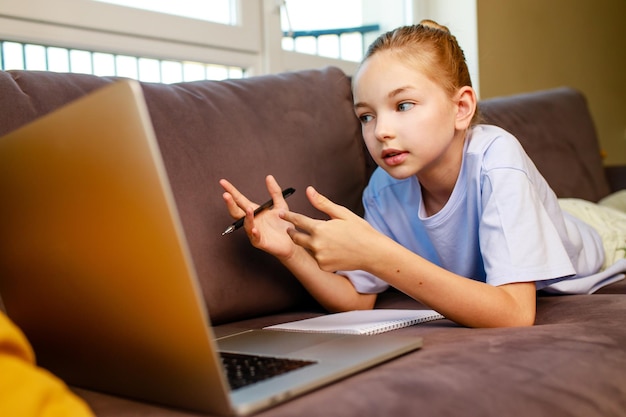 Blonge haar klein meisje met behulp van een laptop thuis huiswerk maken Terug naar school concept