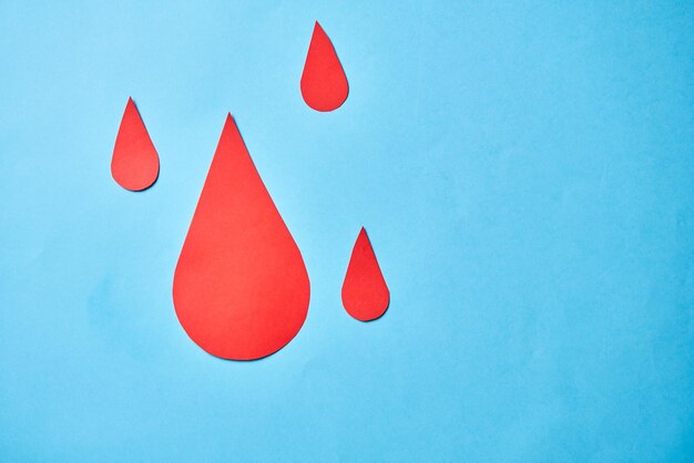 Капля крови, вырезанная из бумаги, переливание крови, Всемирный день донора крови, красный крест, чтобы дать концепцию дня гемофилии в мире крови