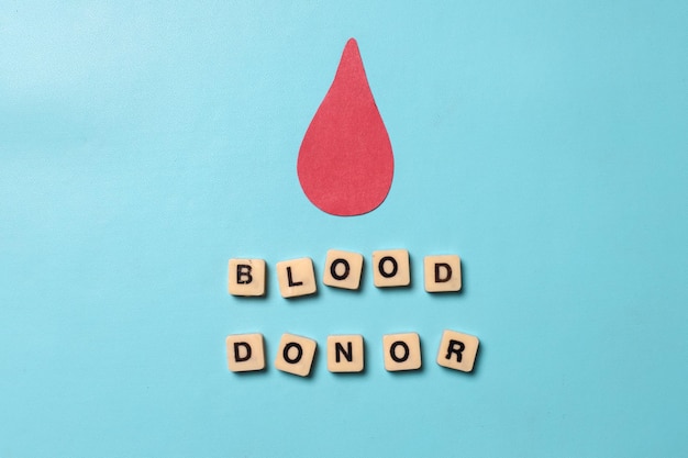 Blood drop paper cutout with blood donor lettering isolated on blue background Concept of Hemophili