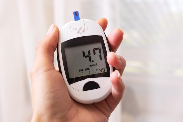 Blood glucose meter in hand on white background