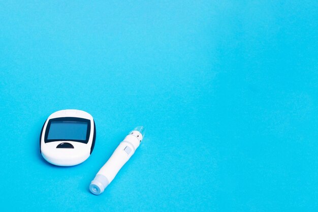 Blood glucose meter and lancet device on blue background