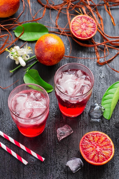 blood orange juice in a glass with ice on a dark background.