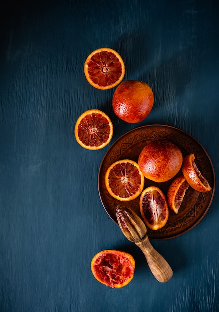 Blood Orange Slices. Halved blood orange with juicer on dark blue background.